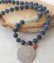 Old silver coin vibrant gemstone necklace on stone