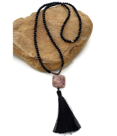 Black and pink gemstone tassel necklace on rock
