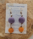 Graduated colorful pom-pom earrings on rock
