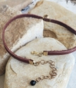 backside closure of brown red leather brass designed bead choker necklace on rocks