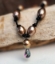 brown pearl necklace knotted on black leather with a rainbow topaz pendant up close