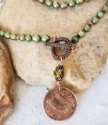 Irish coin pendant green pearl necklace on rock close up