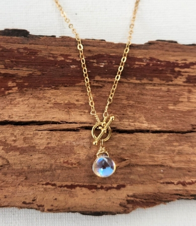 close up rainbow quartz gold chain toggle necklace on wood