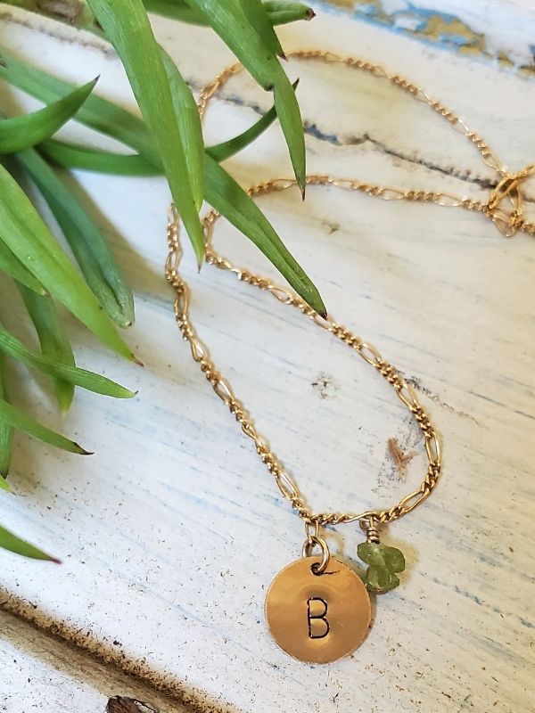 gold chain initial gemstone necklace on trunk with plant