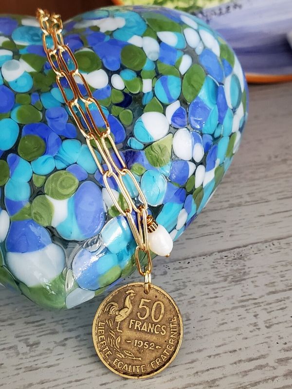 Glass heart on a shelf with french coin necklace
