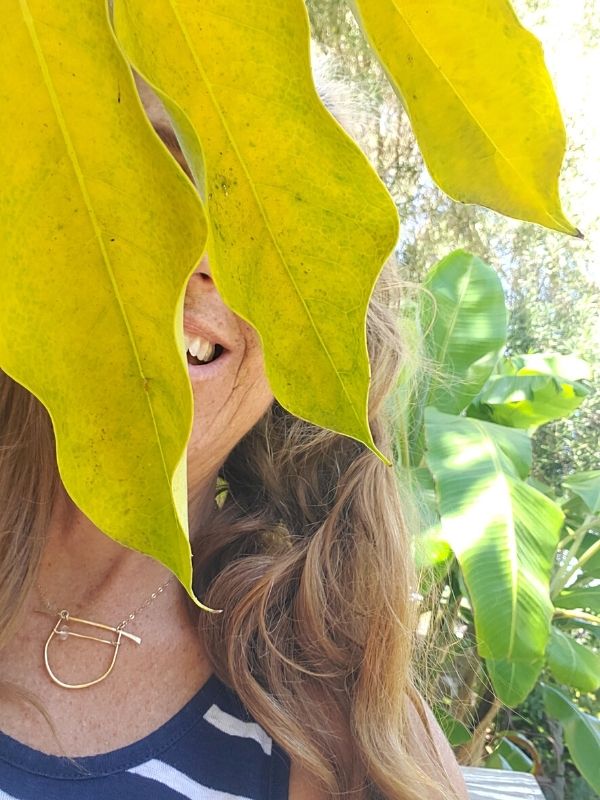 wearing plant leaves & a gold necklace