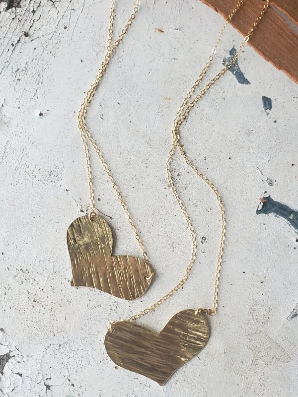 2 gold artisan heart necklaces on table