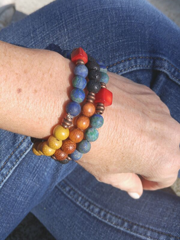 denim crossed legs with a bold color bracelet stack